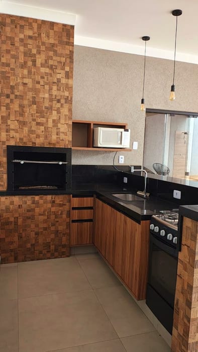 Área gourmet com churrasqueira, fogão e bancada em granito