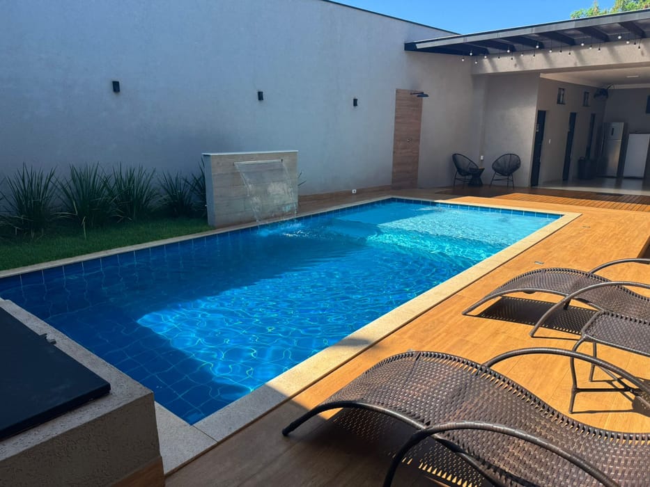 Deck, espreguiçadeiras e a piscina aberta para a área coberta