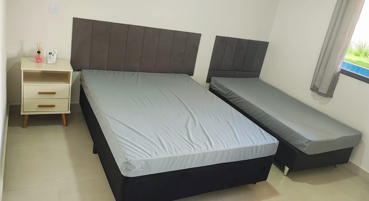 Suíte com cama de casal e cama de solteiro, janela com vista para a piscina